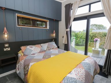 A bedroom with a bed and windows at Coogee View in Maenygroes near New Quay