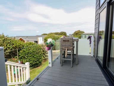 An outdoor deck with a table and stools at Coogee View in Maenygroes near New Quay