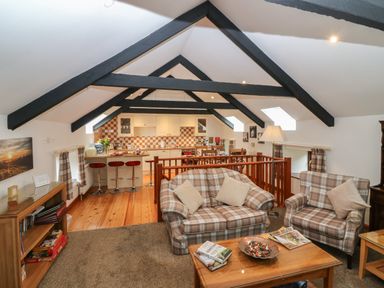 An open plan living room and kitchen with exposed beams and plaid furniture at The Haven in Norham