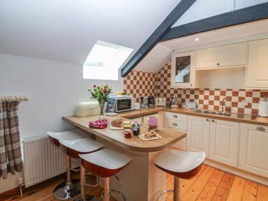 A kitchen with wooden countertops white cabinets and stools at The Haven in Norham