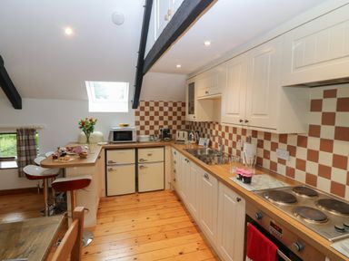 A kitchen with wooden floor cabinets a countertop a stove and bar stools at The Haven in Norham