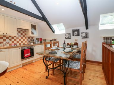 A kitchen with wooden floor and dining table with six chairs at The Haven in Norham