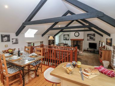 A dining area with table set for four and a living room with fireplace and TV at The Haven in Norham