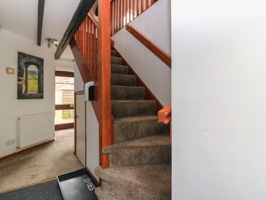 A carpeted staircase with wooden railings in a hallway with a radiator and a wall picture at The Haven in Norham