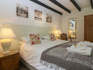 A bedroom with a double bed two bedside lamps a wooden wardrobe and a mirror at The Haven in Norham