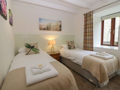 A bedroom with two single beds a window with curtains and a bedside table with a lamp at The Haven in Norham