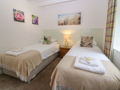 A bedroom with two single beds bedside lamp and floral artwork at The Haven in Norham