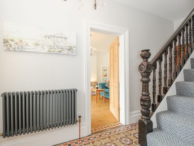 A hallway with a staircase and a patterned tile floor at Albert House in Looe