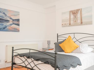 A bedroom with a black metal bed frame and pillows on the bed at Albert House in Looe