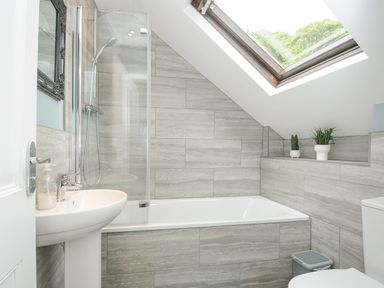 A bathroom with a bathtub sink toilet skylight and two potted plants at Albert House in Looe