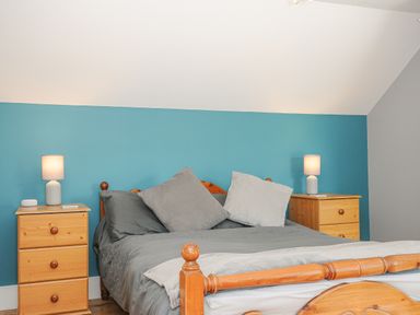 A bedroom with a wooden bed gray bedding and two wooden nightstands with lamps at Albert House in Looe