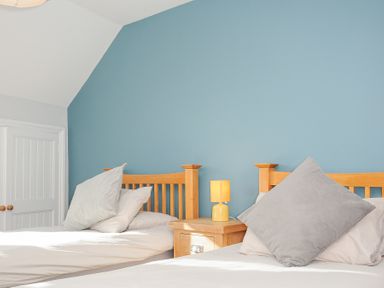 A bedroom with two single beds wooden headboards and a nightstand with a lamp at Albert House in Looe
