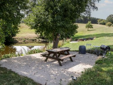 An outdoor area with picnic table and barrel near the water at Poppy in Raglan