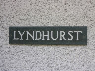 A dark rectangular plaque with the word Lyndhurst on a textured white wall at Lyndhurst Ambleside