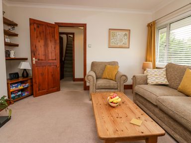 A living room with a sofa and armchair around a wooden coffee table with fruit bowl at Lyndhurst in Ambleside