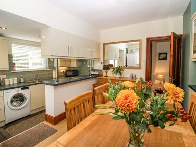 A kitchen and dining area with wooden table chairs and flowers on the table at Lyndhurst in Ambleside