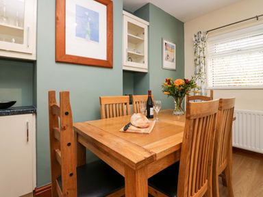 A dining room with a wooden table and chairs a loaf of bread wine glasses and flowers at Lyndhurst in Ambleside