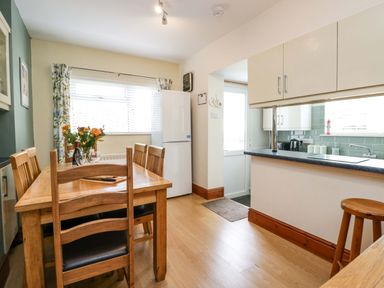 A dining area with a wooden table and chairs next to a kitchen with cabinets and countertop at Lyndhurst in Ambleside