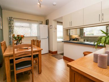 A kitchen and dining area with a wooden table and chairs a white refrigerator and counter at Lyndhurst in Ambleside