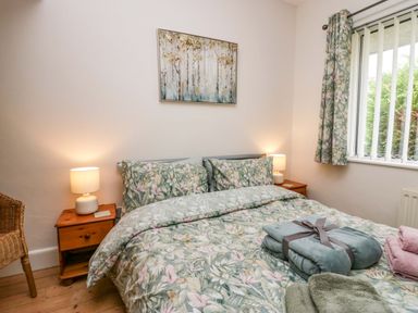 A bedroom with a bed covered in floral bedding with two bedside tables and lamps at Lyndhurst Ambleside