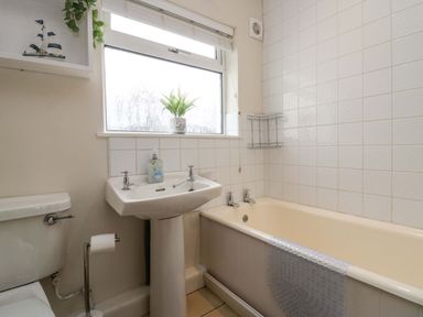A bathroom with a toilet sink bathtub and a window with a plant on the sill at Lyndhurst in Ambleside