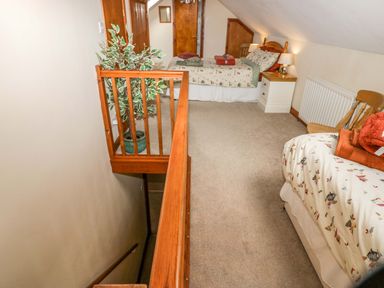 An attic bedroom with two beds a plant near a wooden railing and a staircase at Lyndhurst Ambleside