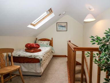 A small attic bedroom with a single bed near a skylight window and wooden railing at Lyndhurst in Ambleside