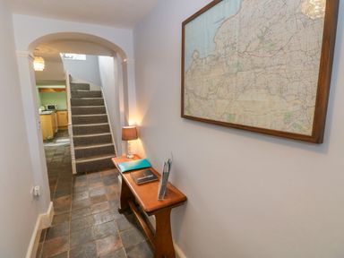 A hallway with tiled floor a wooden bench with a lamp folders and a map on the wall at Orielton Cottage in Dinas Cross