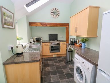 A kitchen with a washing machine oven microwave and refrigerator at Orielton Cottage in Dinas Cross