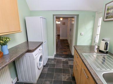 A kitchen with a washing machine refrigerator sink kettle and countertop at Orielton Cottage in Dinas Cross