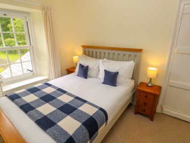 A bedroom with a double bed two bedside tables with lamps and a window at Orielton Cottage in Dinas Cross