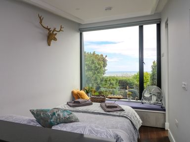 A bedroom with a bed near a large window with plants and a fan at Sunriser in Tara Hill near Ballymoney County Wexford