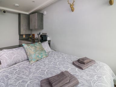 A bedroom with a bed with patterned bedding and folded towels next to a small kitchen area with cabinets and a coffee machine at Sunriser Tara Hill near Ballymoney County Wexford