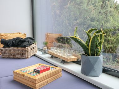 A window seat with a plant in a gray pot candles in glass holders on a wooden tray a wicker basket with cushions and clothing and a wooden box with a pack of playing cards on Sunriser in Tara Hill near Ballymoney County Wexford