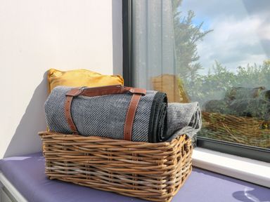 A wicker basket with rolled blankets and a yellow cushion on a window seat at Sunriser in Tara Hill near Ballymoney County Wexford