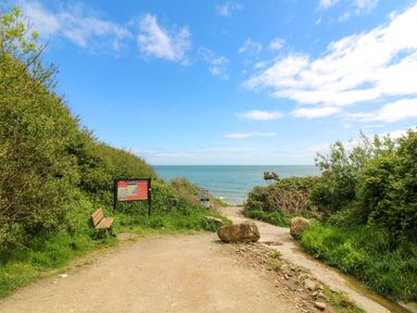 A coastal path with bushes a bench and information boards leading to the sea at Sunriser in Tara Hill near Ballymoney County Wexford