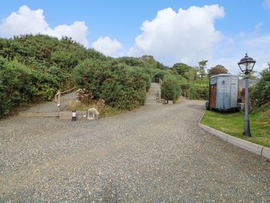 A gravel pathway with steps and bushes along the sides with a trailer and a lamppost on grass at Sunriser Tara Hill near Ballymoney County Wexford