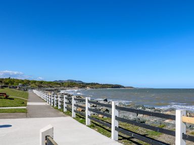 A concrete walkway along a rocky coastline with a fence and grassy area at Sunriser in Tara Hill near Ballymoney County Wexford
