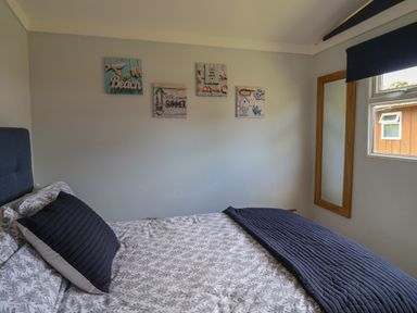 A bedroom with a bed pillow wall art mirror and window at Pebble Beach Chalet in Seaton