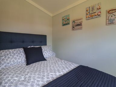 A bedroom with a bed and beach themed wall art at Pebble Beach Chalet in Seaton