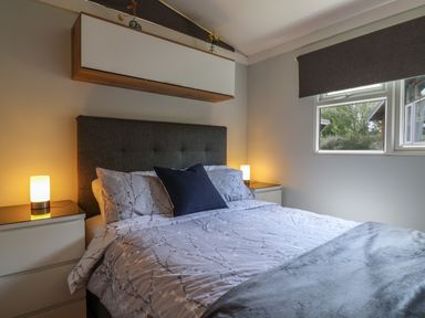 A bedroom with a bed and bedside tables with lamps near a window at Pebble Beach Chalet in Seaton