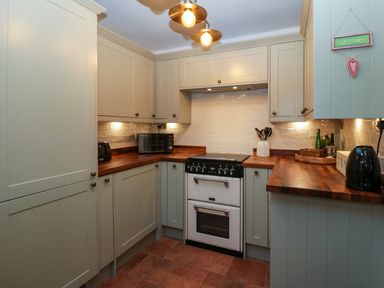 A kitchen with cabinets a stove microwave toaster and kettle at Holly Cottage in Great Malvern