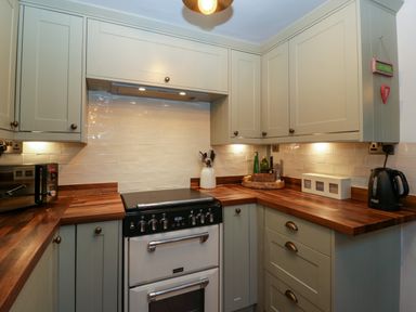 A kitchen with wooden countertops an oven microwave kettle and cabinets at Holly Cottage in Great Malvern