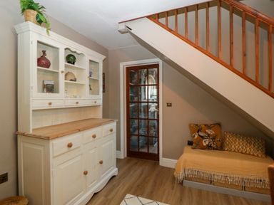 A room with a white cabinet and a seating area under a staircase at Holly Cottage in Great Malvern