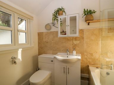 A bathroom with a toilet sink cabinet mirror and bathtub at Holly Cottage in Great Malvern