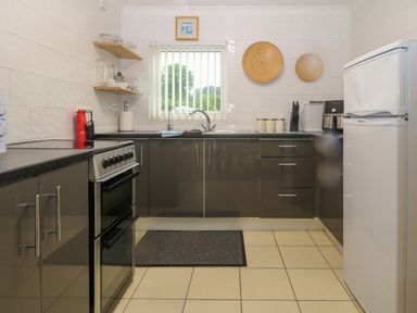 A kitchen with gray cabinets stove refrigerator and window with blinds at 245 Riverside Lodge in Caeathro
