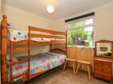 A bedroom with wooden bunk beds two wooden chairs and a wooden dresser with a mirror at 245 Riverside Lodge in Caeathro