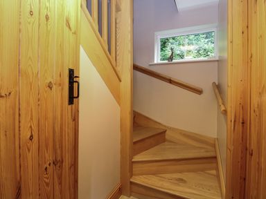 A wooden staircase with a window and handrails in a hallway at Dairy Cottage in West Caister near Caister-on-Sea