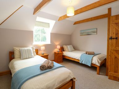A bedroom with two single beds bedside tables lamps and a window at Dairy Cottage in West Caister near Caister-on-Sea