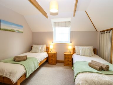 A bedroom with two single beds bedside tables and a window at Dairy Cottage in West Caister near Caister-on-Sea